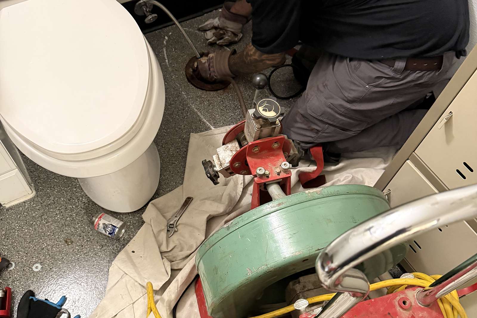 Technician running a drain machine at a pulled toilet