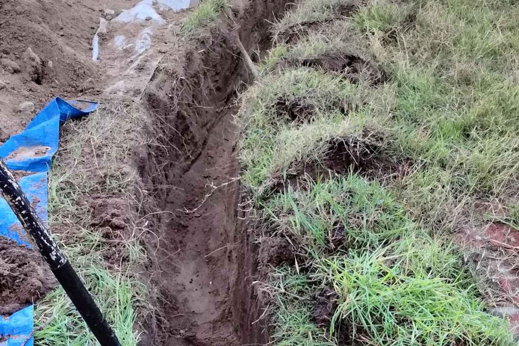 Sewer trench dug alongside a lawn