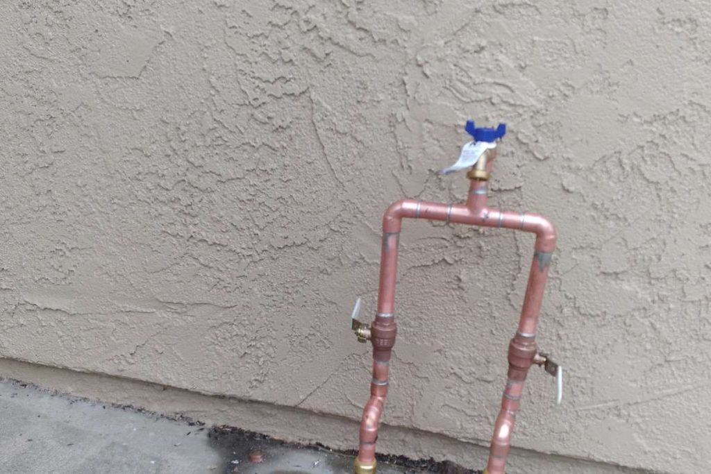 New copper hose bib loop installed on an exterior wall