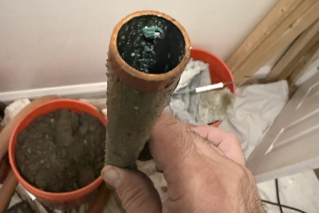 Section of failed copper pipe cut out from under a floor