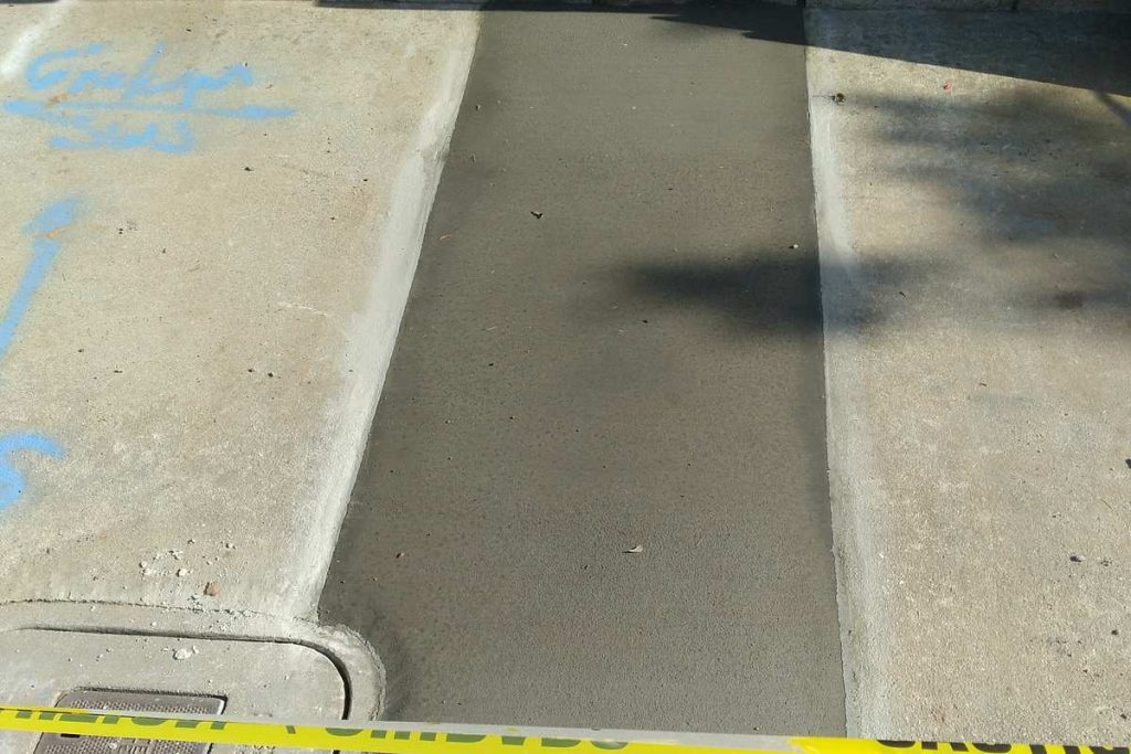 Fresh concrete patch beside a block wall
