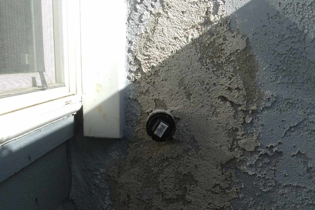 Cleanout plug set into a patched stucco wall