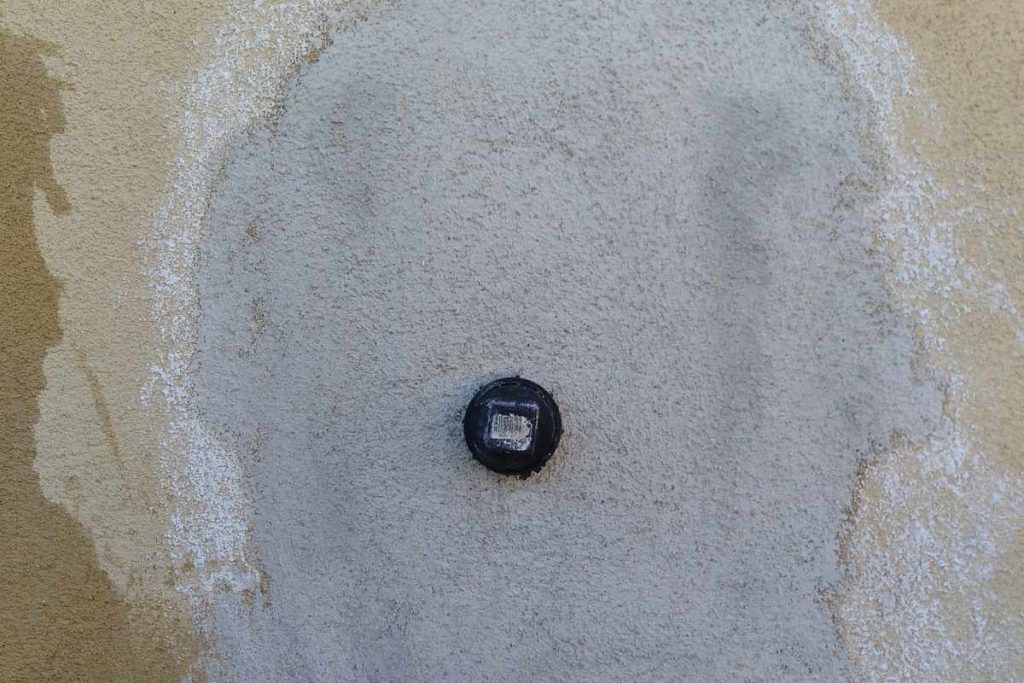 Cleanout cap finished flush in a new stucco patch