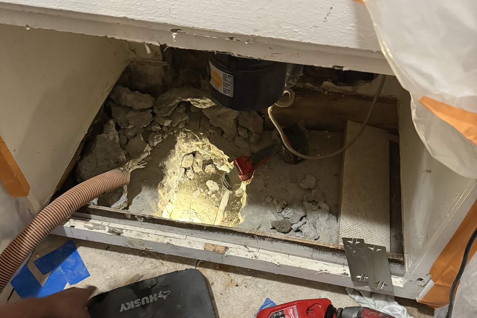 Technician working under a cabinet during a slab leak repair