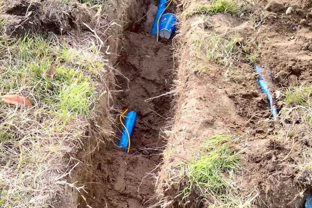 Long sewer trench running down a sloped yard