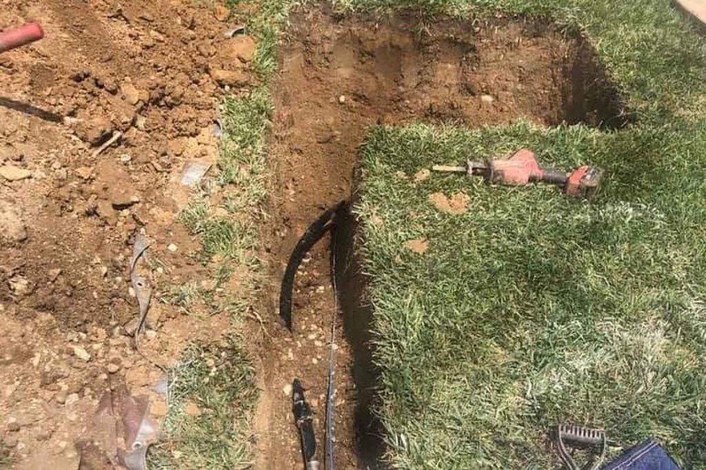 Sewer trench with a new cleanout box in a lawn