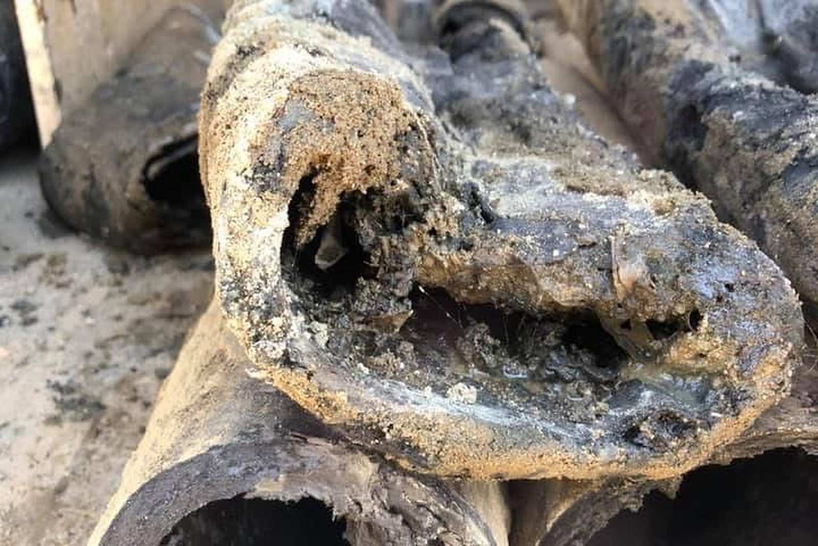 Close-up of scale build-up inside an old cast iron pipe