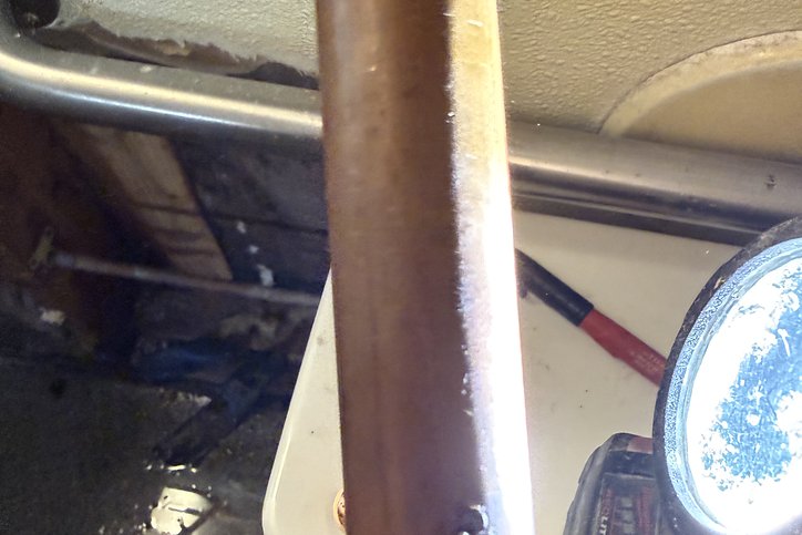 Technician inspecting a cast iron pipe with a work light