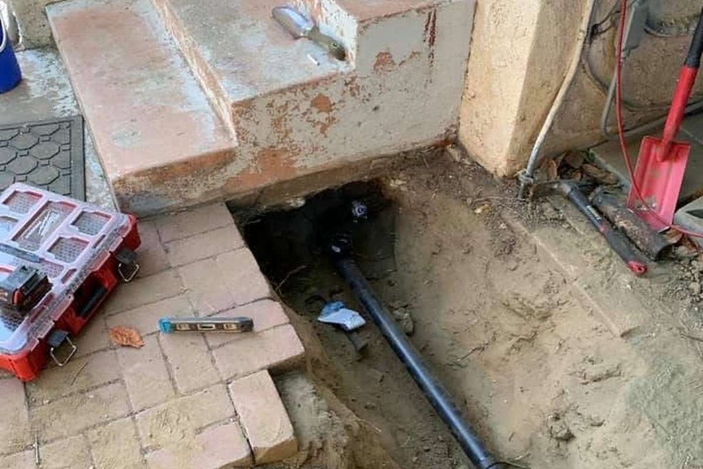 Sewer line exposed beside a patio stairway