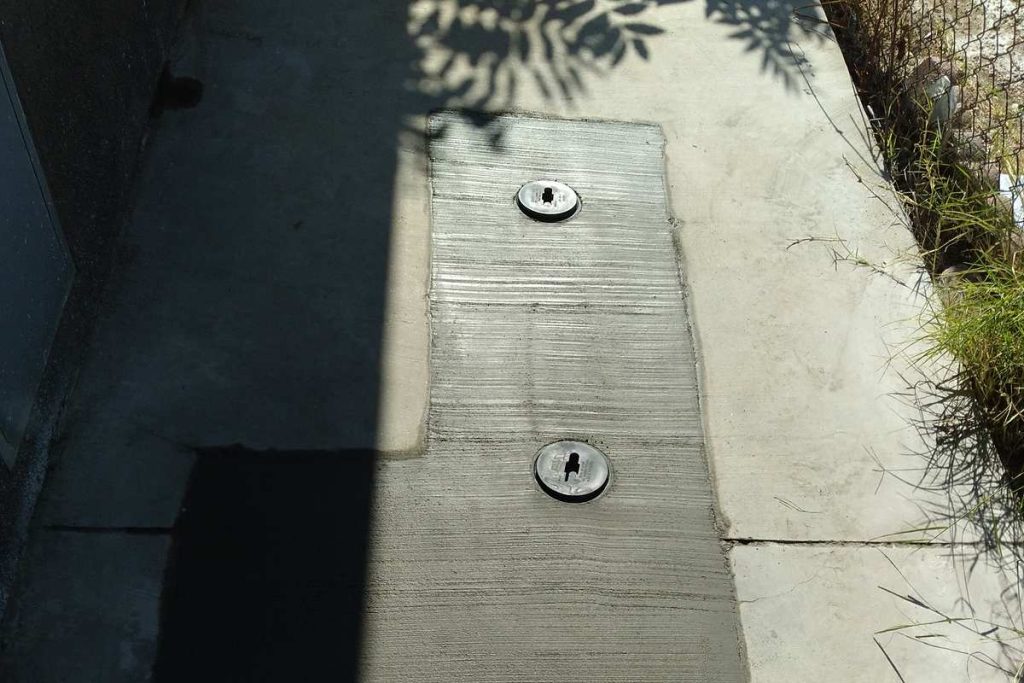 Concrete patch with two cleanout caps in a side yard