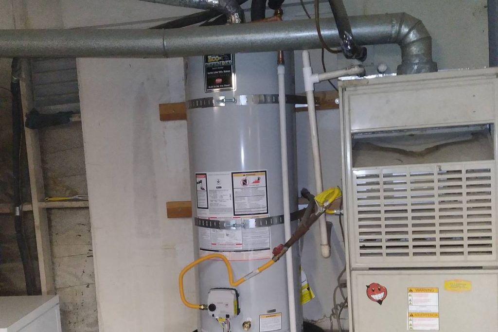 Water heater standing beside a furnace in a garage